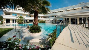 A pool area with a palm tree, a covered walkway, and a building with multiple windows. - 14 Relais du Lac Charme - Italian Homing (Desenzano del Garda)