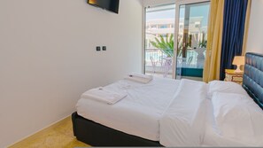 Ein Hotelzimmer mit Bett, einem an der Wand befestigten Fernseher und Blick auf den Balkon.