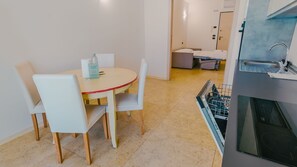 Ein kleines Hotelzimmer mit Essbereich, einer Küchenzeile und einem Bett.