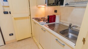 Eine kleine Küche mit Herd, Spüle und einer Mikrowelle über der Arbeitsfläche.