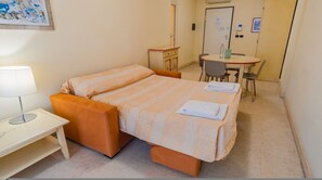 A hotel room with a bed, a desk with a lamp, a chair, and a small table. - 116 Relais du Lac Village - Italian Homing (Desenzano del Garda)