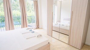 A modern bedroom with a large bed, a bedside table with towels, and a view of a balcony. - 20 Relais du Lac Elite - Italian Homing (Desenzano del Garda)