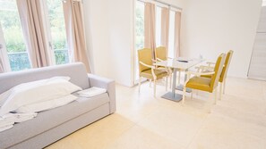 Ein modernes Hotelzimmer mit einem grauen Sofa, einem kleinen Tisch und gelben Stühlen.