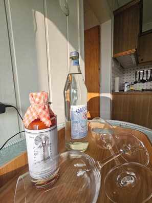 Eine Küchenzeile mit einer Gerolsteiner-Flasche, einem Marmeladenglas und leeren Weingläsern auf einem Tisch.