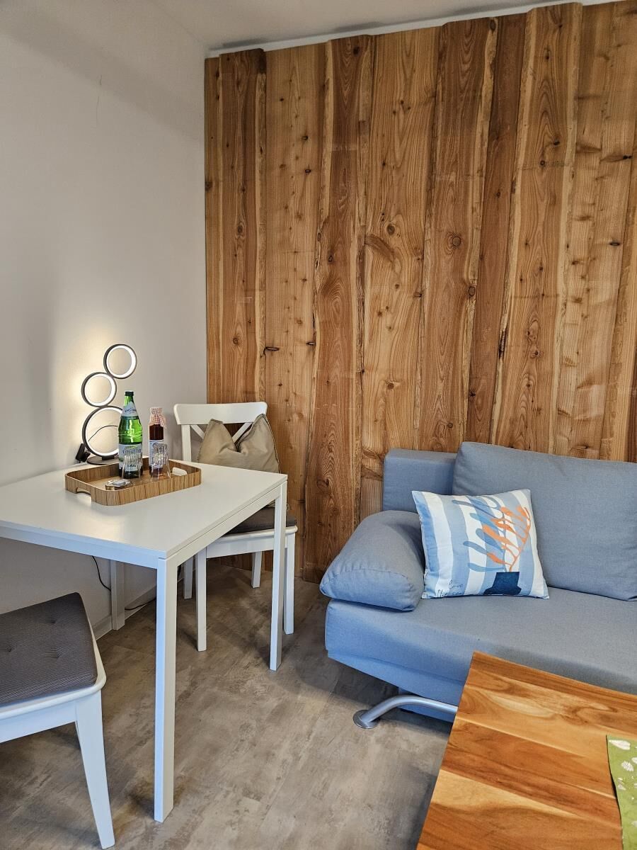 Ein Zimmer mit einem weißen Tisch, einem blauen Sofa und einer Holzwand.