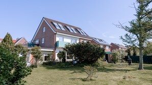 Una casa residencial con techo inclinado, paneles solares y un césped bien cuidado.