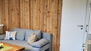 Una sala de estar moderna con un sofá gris, un panel de pared de madera y una mesa de centro de madera.