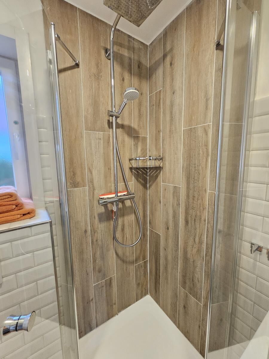 A shower with a rain shower head, a handheld showerhead, and a handheld shower attachment.