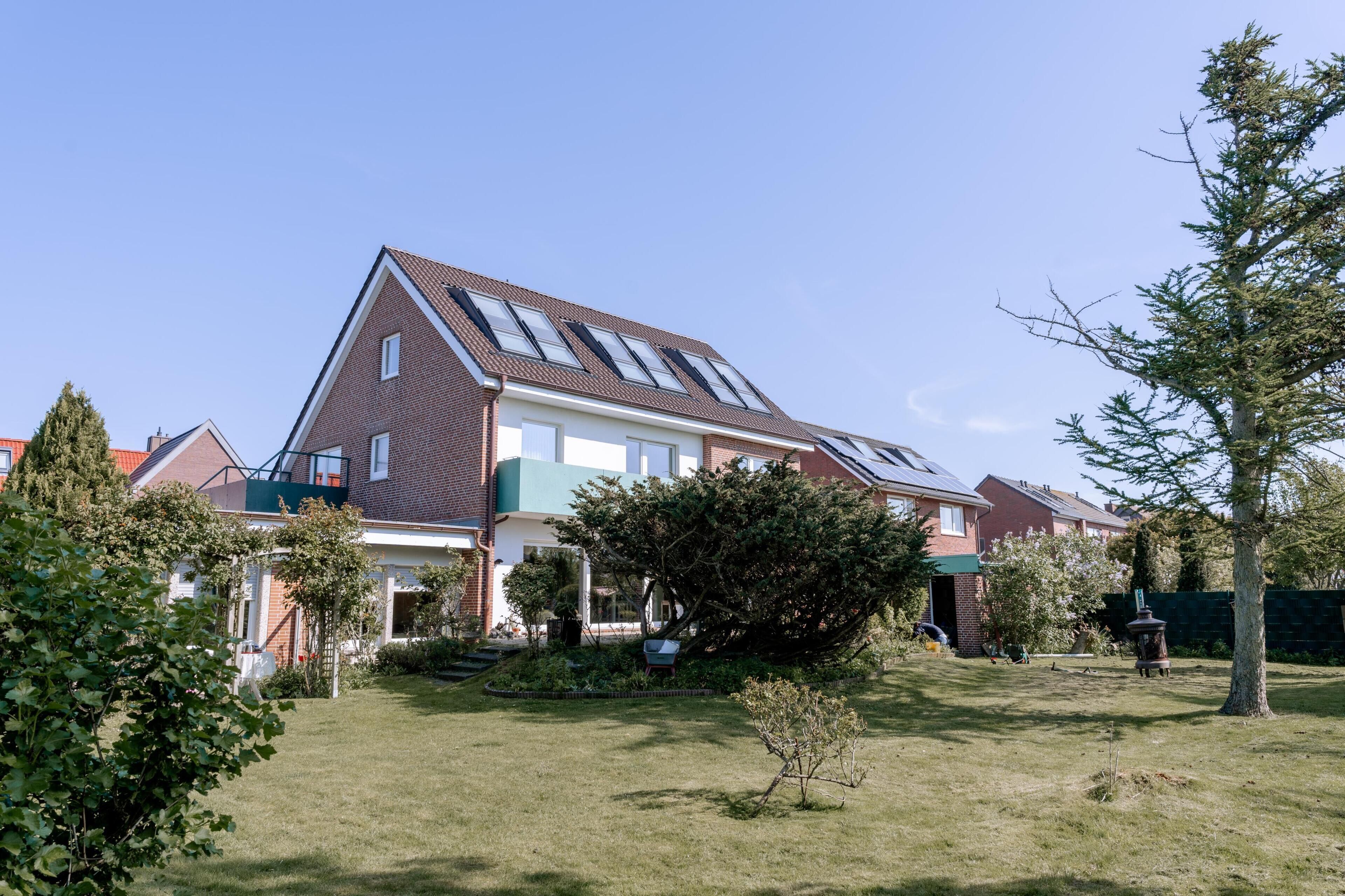 Ein Wohnhaus mit Satteldach, Solaranlage und gepflegtem Rasen.