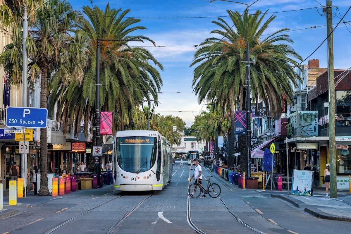 Un tram percorre una strada con palme, negozi e un cartello che indica 250 posti auto.