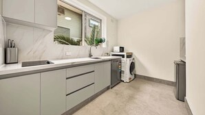 Una cocina compacta con lavavajillas integrado, microondas y ventana con persianas.