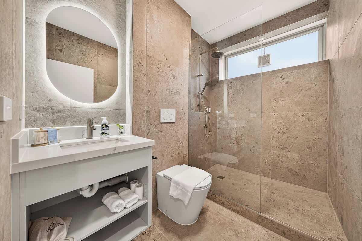 Une salle de bain moderne avec une douche, un lavabo avec un miroir et des toilettes.