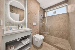 Une salle de bain moderne avec un grand miroir, une douche et des toilettes.