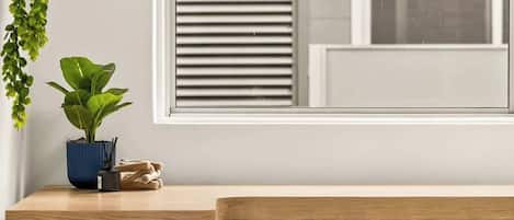 Ein Zimmer mit einem Holztisch, einer Topfpflanze und einem Hocker.