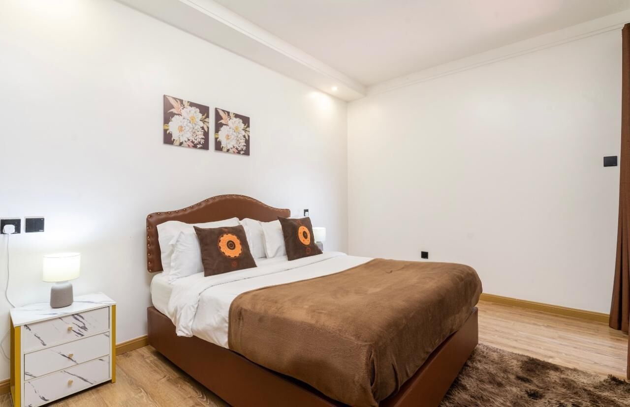 A bedroom with a bed, nightstand, and wall art.