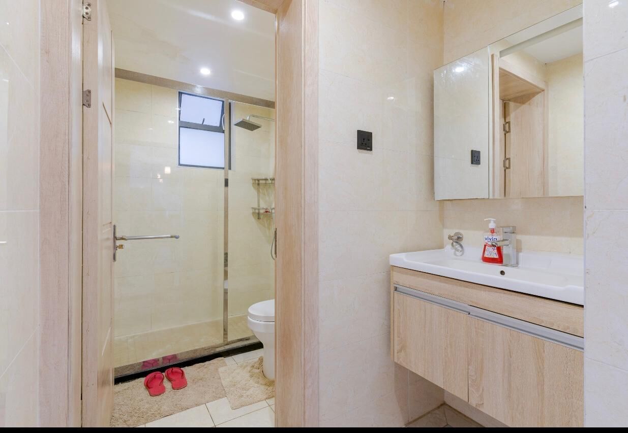 A bathroom with a glass shower enclosure, a white sink with a mirror, and a toilet.