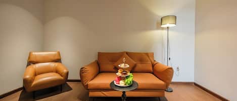 A modern living room with a leather sofa, a matching armchair, and a small round table with a lamp.