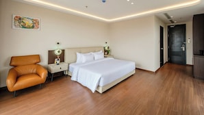 Una moderna camera d'albergo con un letto grande, un divano, un comodino con una lampada e un quadro appeso al muro.