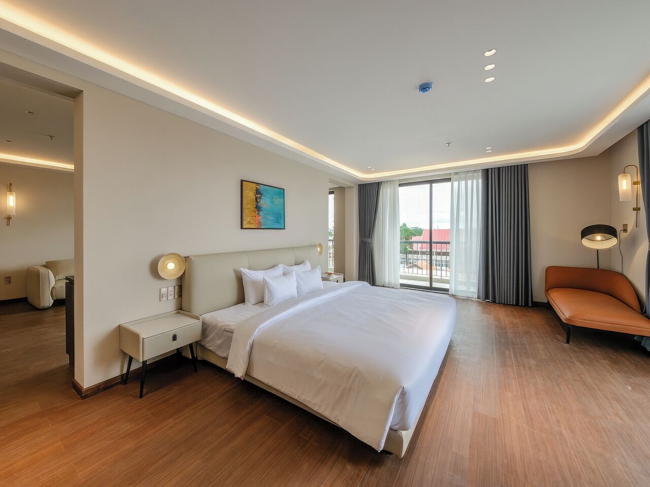 Une chambre d’hôtel avec un grand lit, des tables de chevet, un canapé et une vue sur l’extérieur.