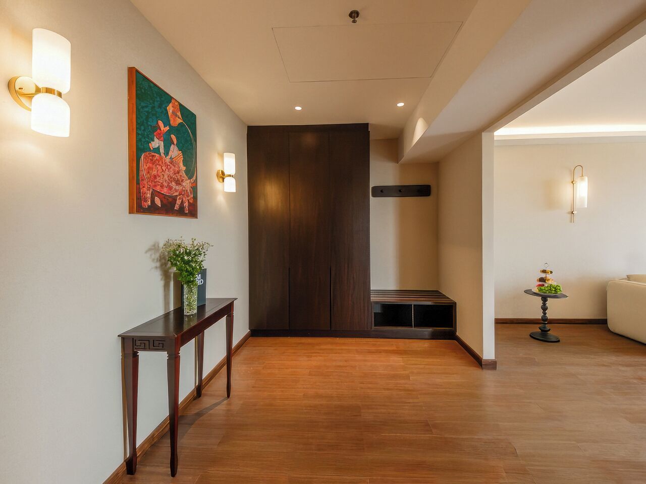 Ein Flur mit Holzboden, einer dunklen Holzvertäfelung, einem kleinen Tisch mit einer Vase und einem Gemälde an der Wand.