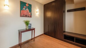 Un'accogliente hall d'albergo con pavimento in legno, un tavolo consolle con un vaso, luci a parete, un quadro e un grande armadio in legno.