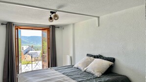 A bedroom with a bed, curtains, and a view of the outdoors. - Les Cariolettes Lodge (Font-Romeu-Odeillo-Via)