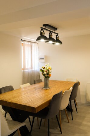 A dining area with a wooden table, six chairs, and a vase of flowers. - Les Cariolettes Lodge (Font-Romeu-Odeillo-Via)
