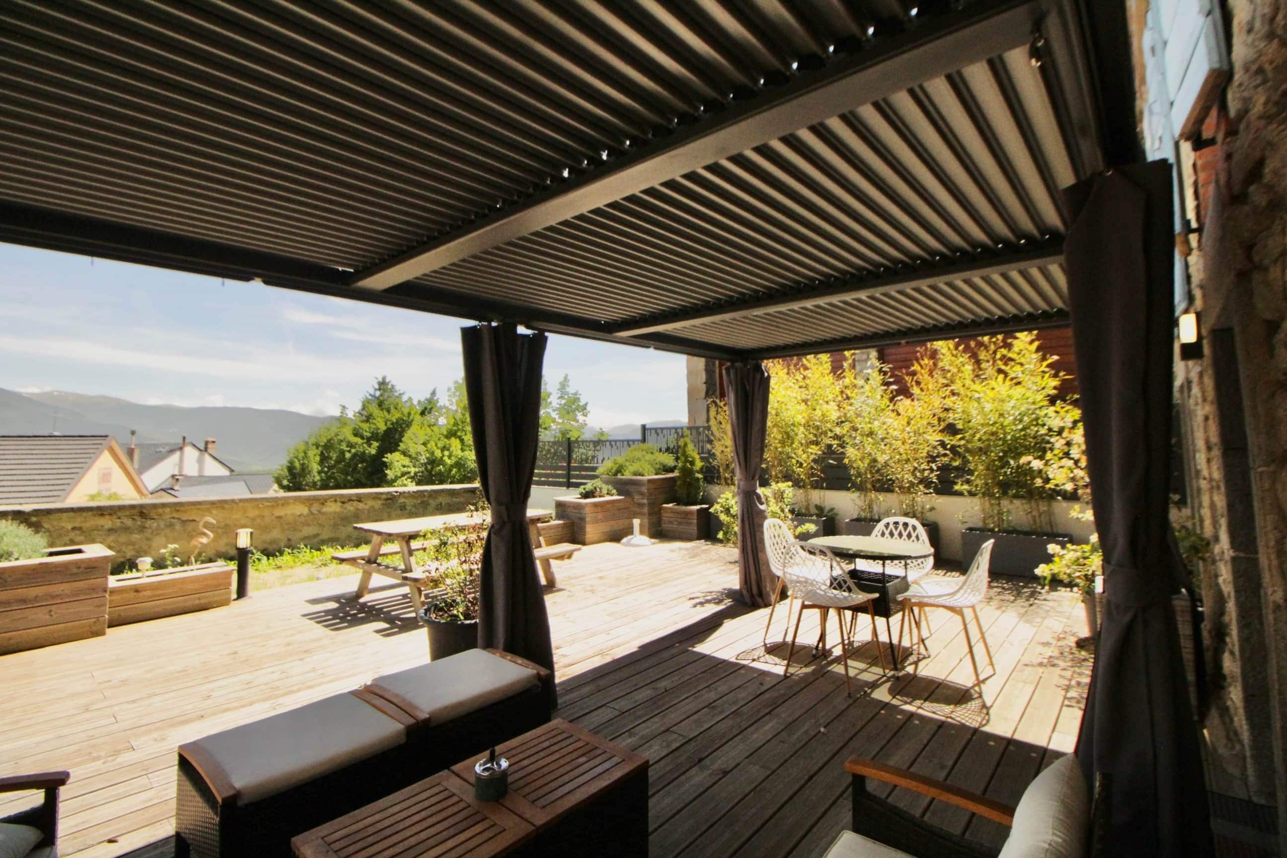 An outdoor patio with a wooden deck, a table with chairs, and a covered seating area.