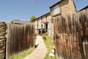 A wooden gate leading to a stone building with a balcony and a wooden pathway. - Les Cariolettes Lodge (Font-Romeu-Odeillo-Via)