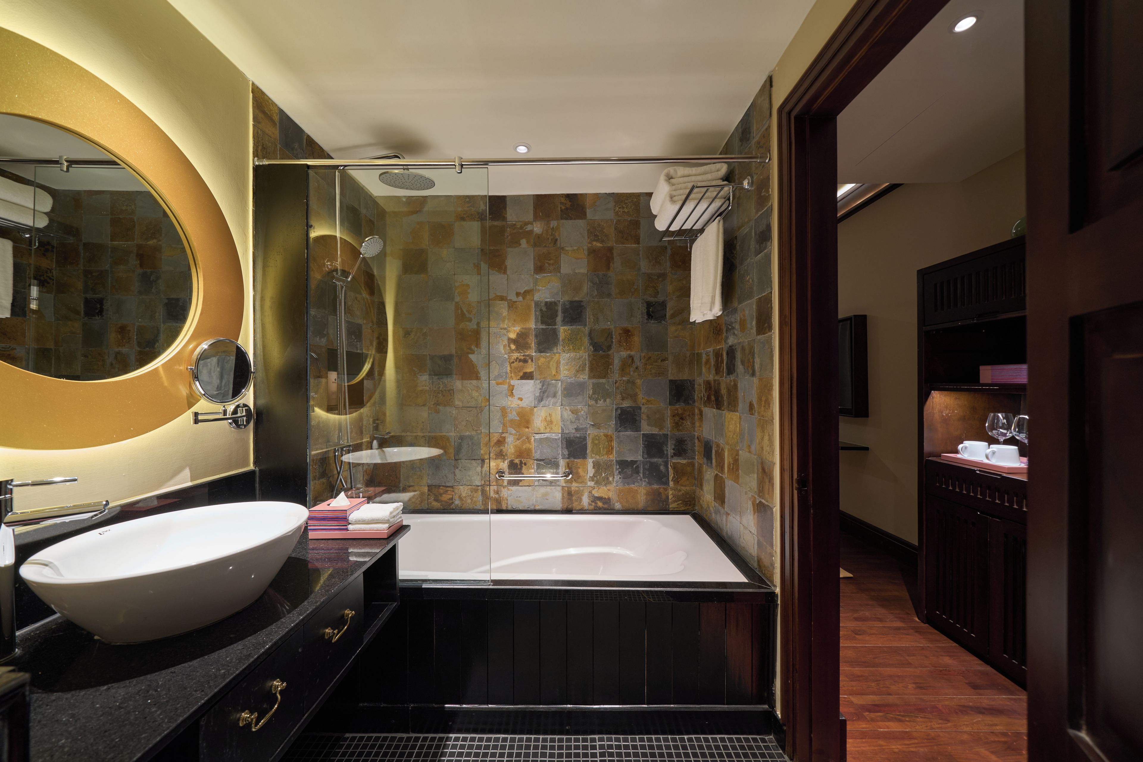 Un baño moderno con un lavamanos ovalado grande, una bañera y una zona de ducha.