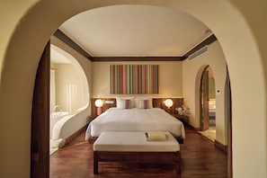 A hotel room with a large bed, a bench, a bedside table with a lamp, and a view through an arched doorway. - The Myst Sapa Resort (Sa Pa)