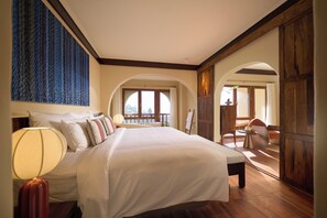 Un dormitorio amplio con una cama grande, vista al exterior por una ventana y piso de madera.