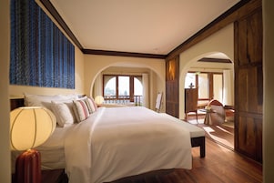 Un dormitorio amplio con una cama grande, vista al exterior por una ventana y piso de madera.