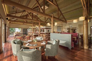 A spacious dining area with wooden beams, a high ceiling, and a view of the outdoors.