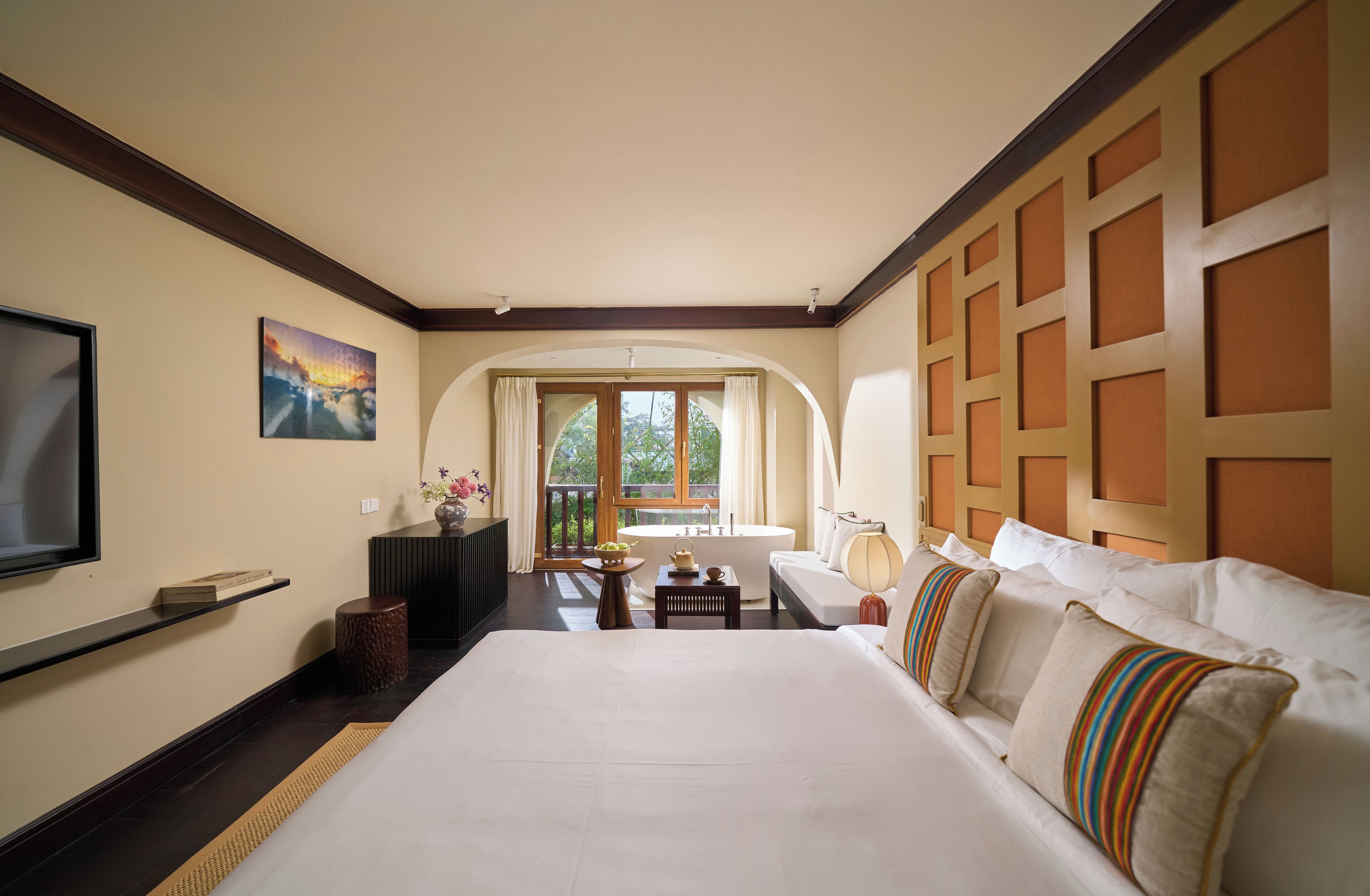 Habitación de hotel con una cama grande, televisor, escritorio y vistas al exterior.