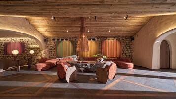 Un espacio de descanso acogedor con pared de piedra, techo de madera y una distribución central de asientos.