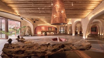 A spacious lobby with a wooden ceiling, a central stone feature, and a sign indicating an exit.