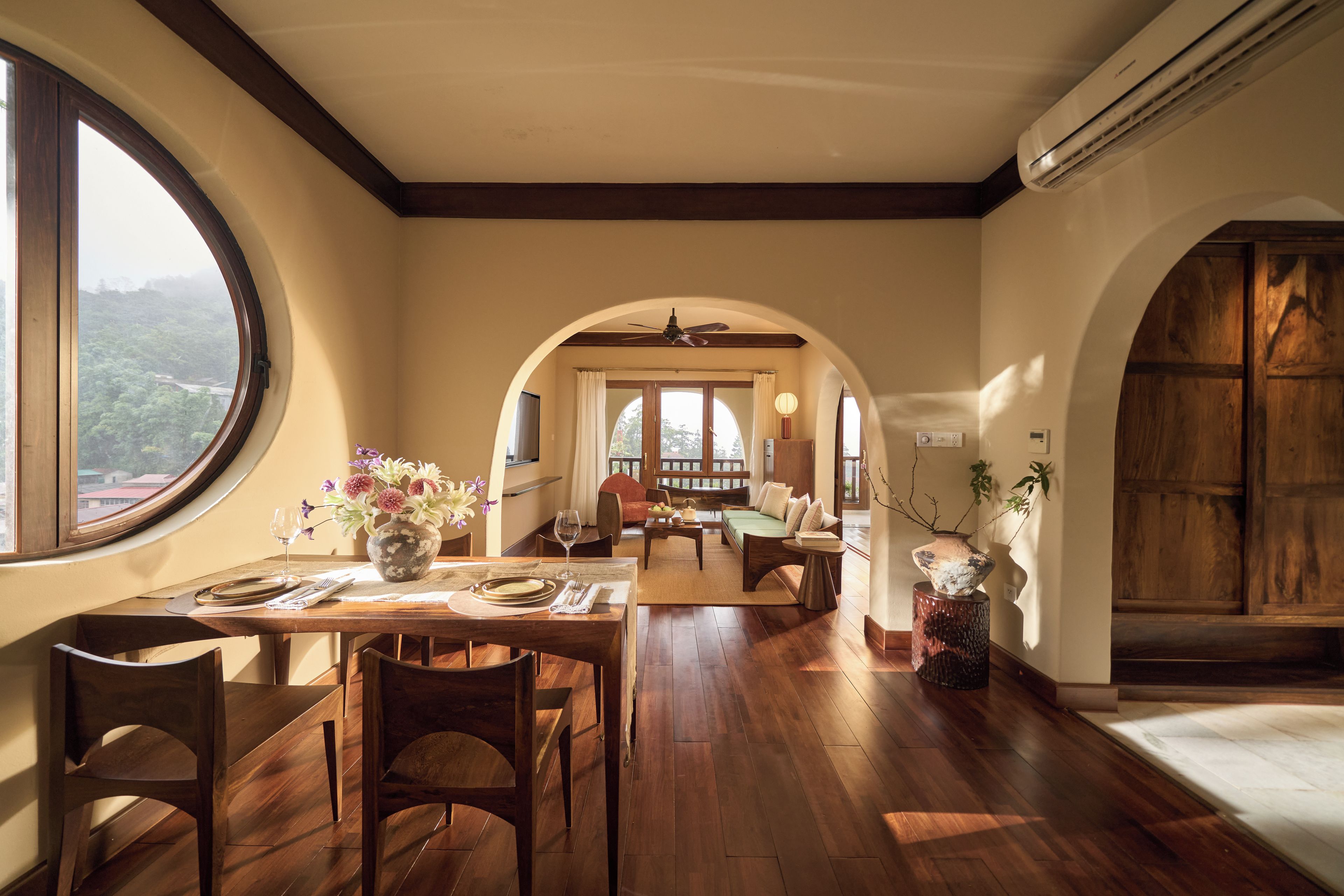 Un comedor amplio con un gran ventanal, suelo de madera y vistas al exterior.