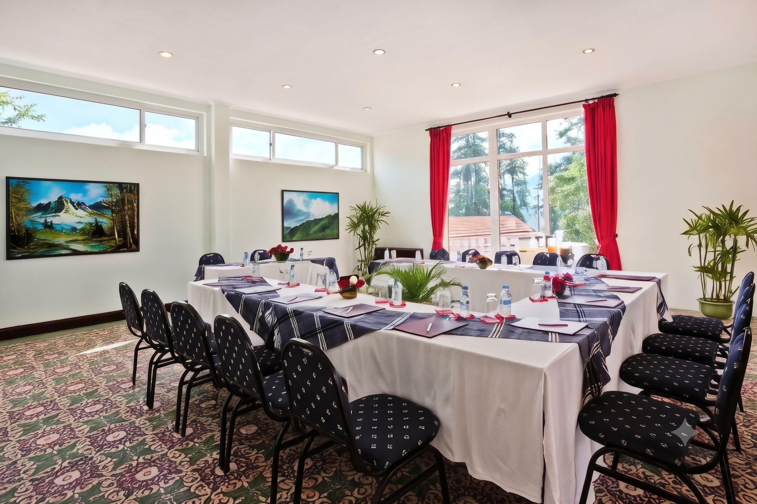 Un salón de conferencias con una larga mesa, sillas y dos cuadros en las paredes.