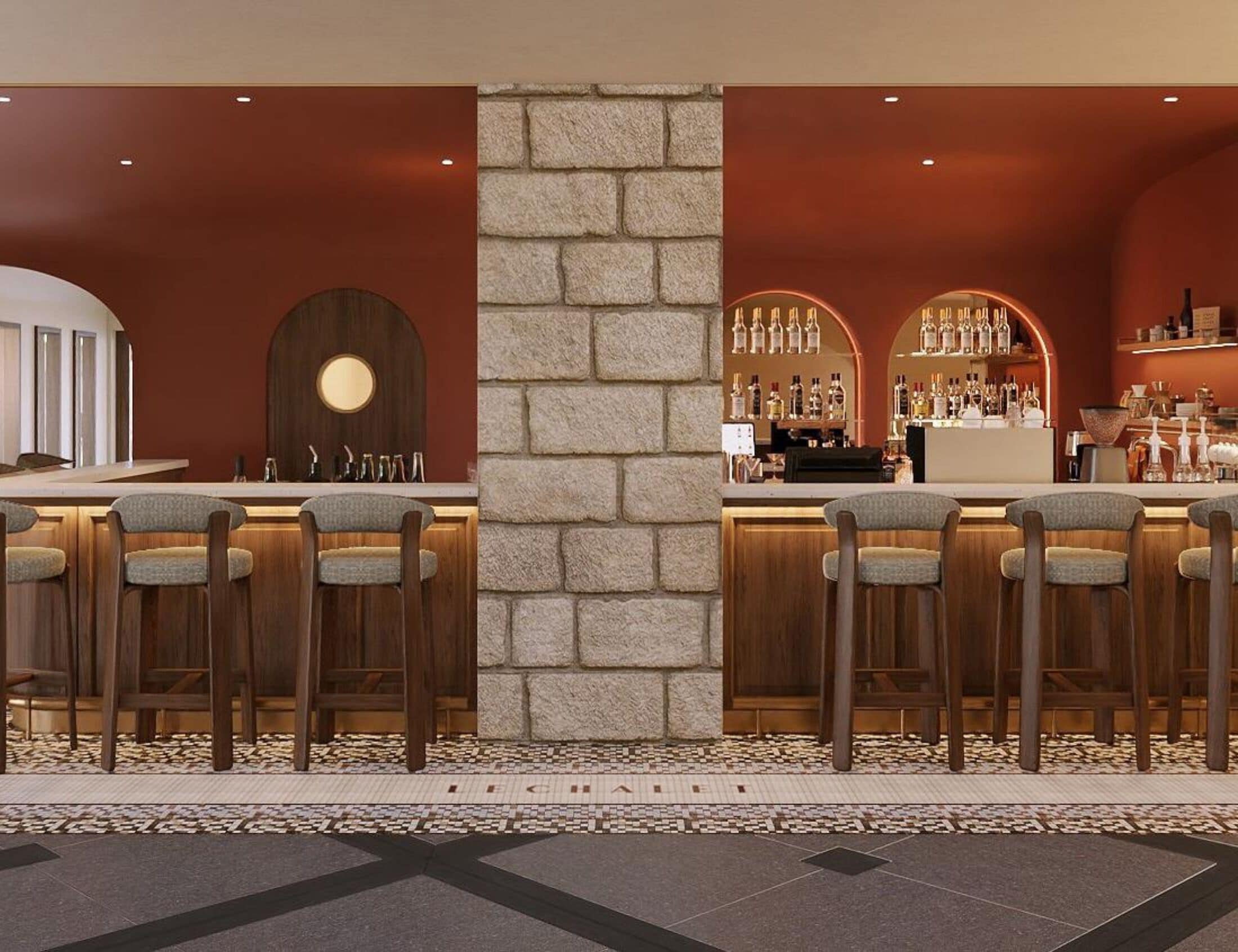 Zona de bar con taburetes altos, un pilar de piedra y una exhibición de botellas.
