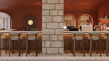 Zona de bar con taburetes altos, un pilar de piedra y una exhibición de botellas.