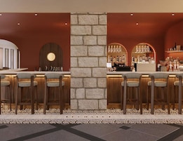A bar area with high stools, a stone pillar, and a display of bottles.