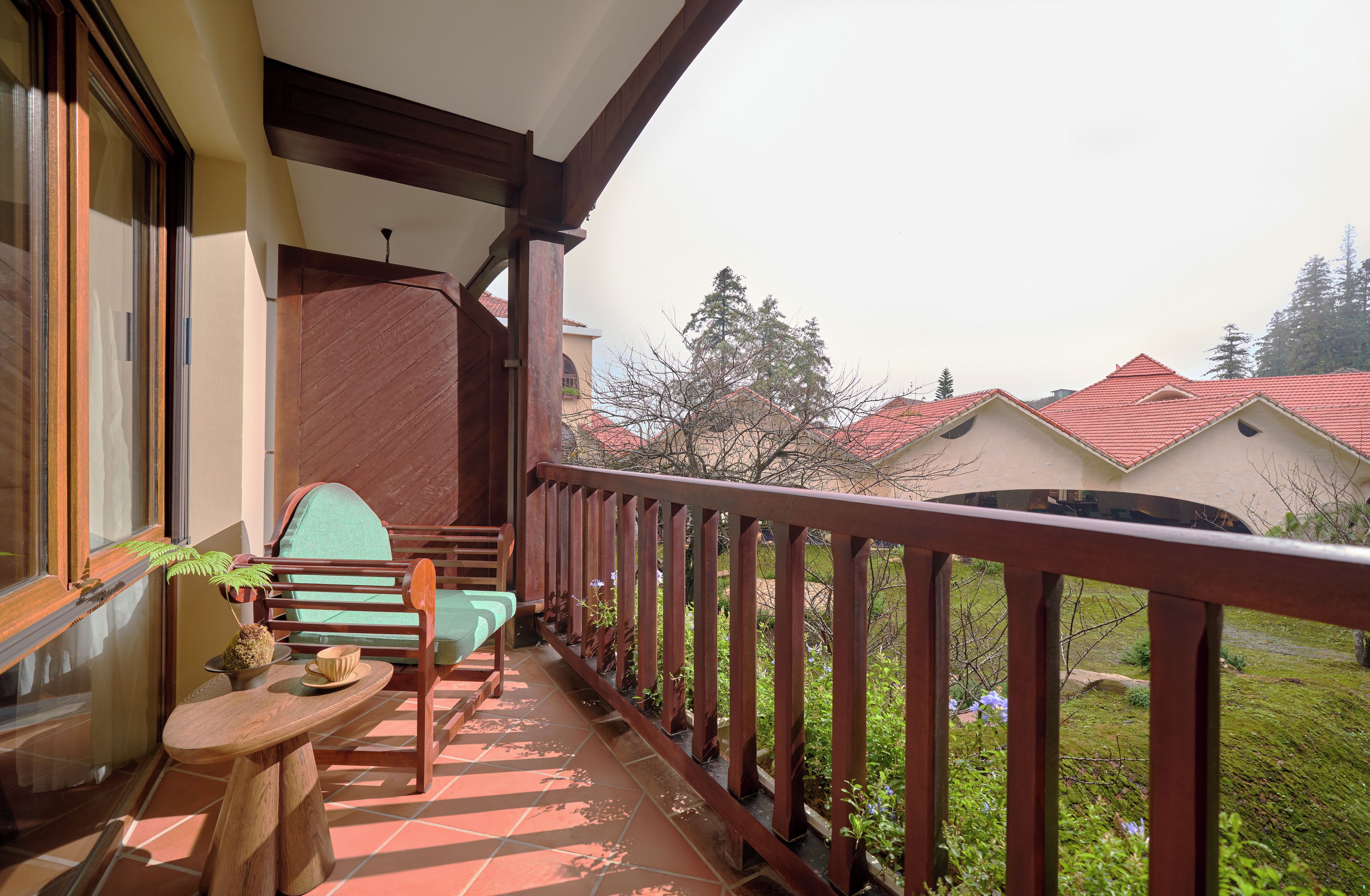 A balcony with a wooden chair, a small table, and a potted plant.