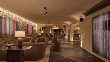 A spacious lobby with a stone wall, a seating area with sofas and armchairs, and a patterned wall.