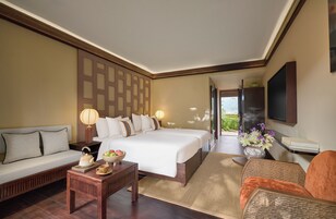 Habitación de hotel con cama, sofá y una mesita con un frutero.