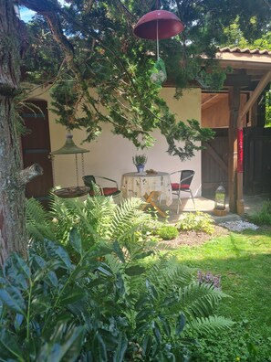 Ein Garten mit Tisch und Stühlen, einem Vogelhäuschen und einer Holzhütte.