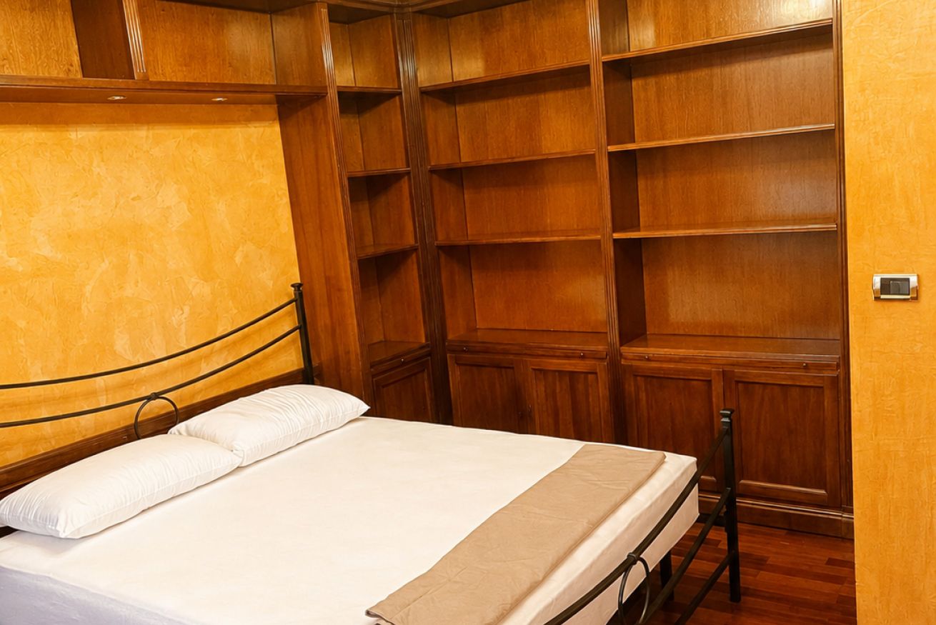 A bedroom with a bed, wooden wardrobe, and a small table.