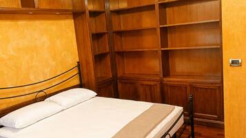 A bedroom with a bed, wooden wardrobe, and a small table.