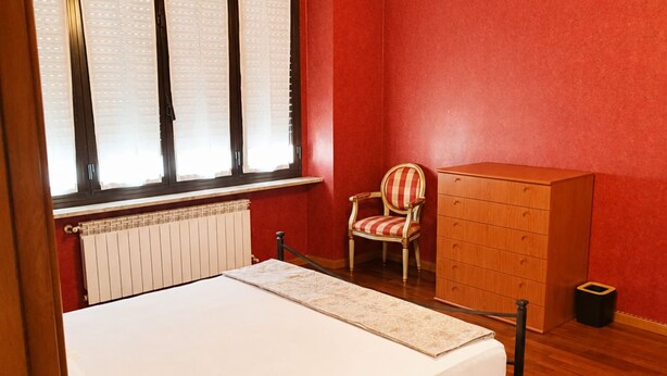 A room with a bed, a chair, a dresser, and a radiator. - The City Gateway: Cozy Stay in Torino (Torino)