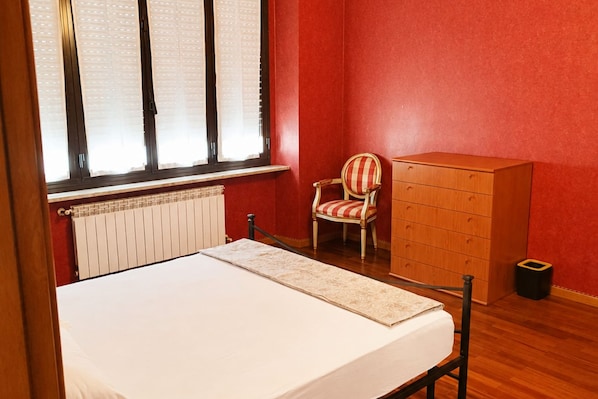 Une pièce comprenant un lit, une chaise, une commode et un radiateur.